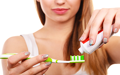A woman placing toothpaste onto a toothbrush