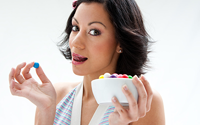 Happy woman eating candy out of a bowl