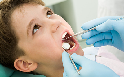 A young boy having his teeth looked at