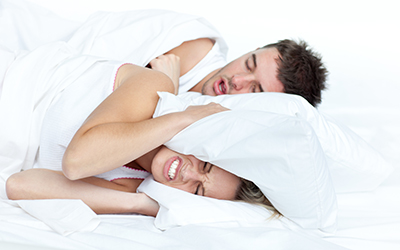 A woman sleeping next to a man snoring
