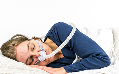 A woman sleeping on her side wearing a cpap machine