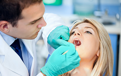 A dentist working on a female patients mouth