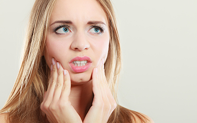 A woman holding her jaw in pain