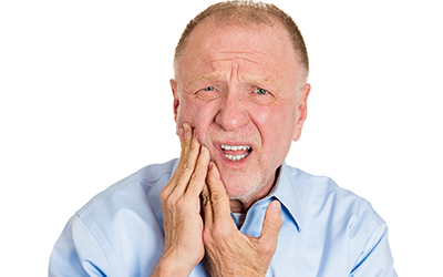 An older man holding the side of his mouth in pain