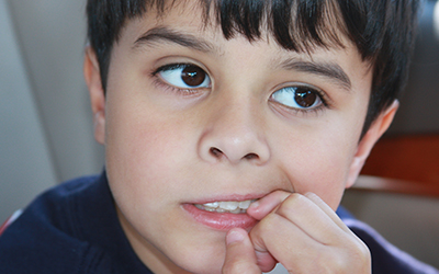 A young boy biting his fingernails