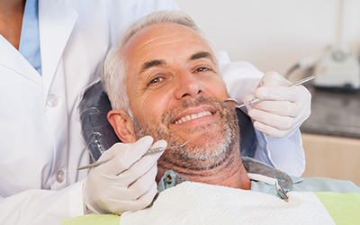 A dentist examining an older mans teeth